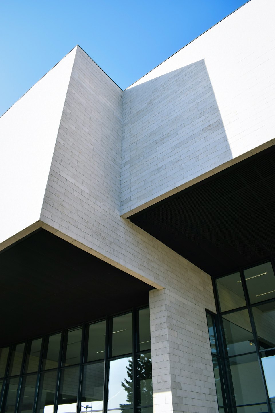 Modernes Gebäude aus Stein und Glas mit geometrischen Fensterschatten.