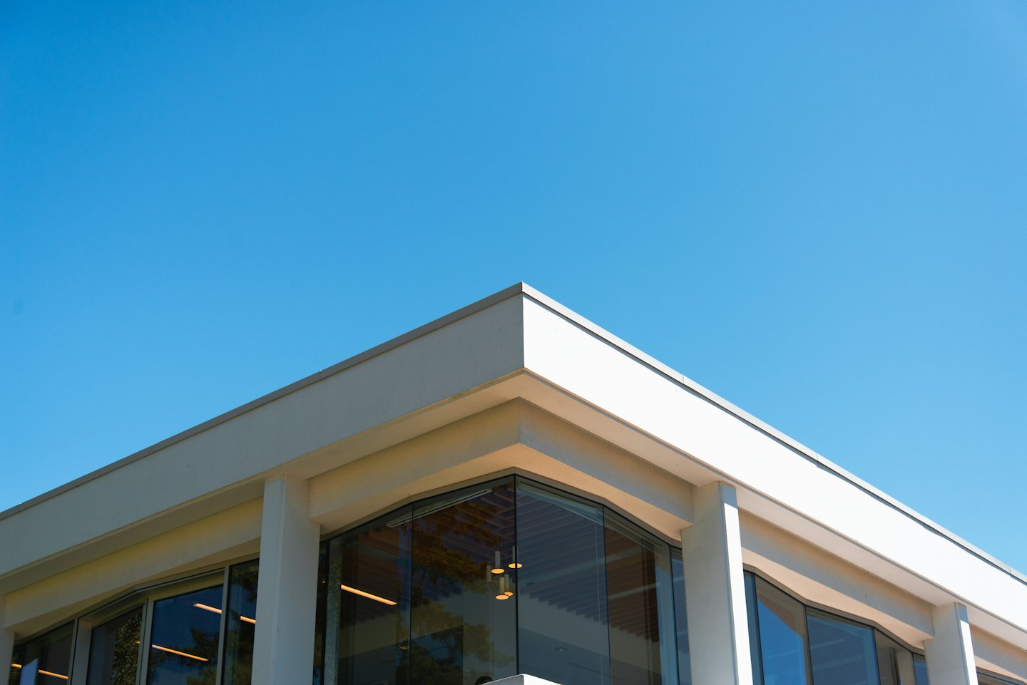 Moderne Gebäudeecke mit großen Glasfenstern unter blauem Himmel.