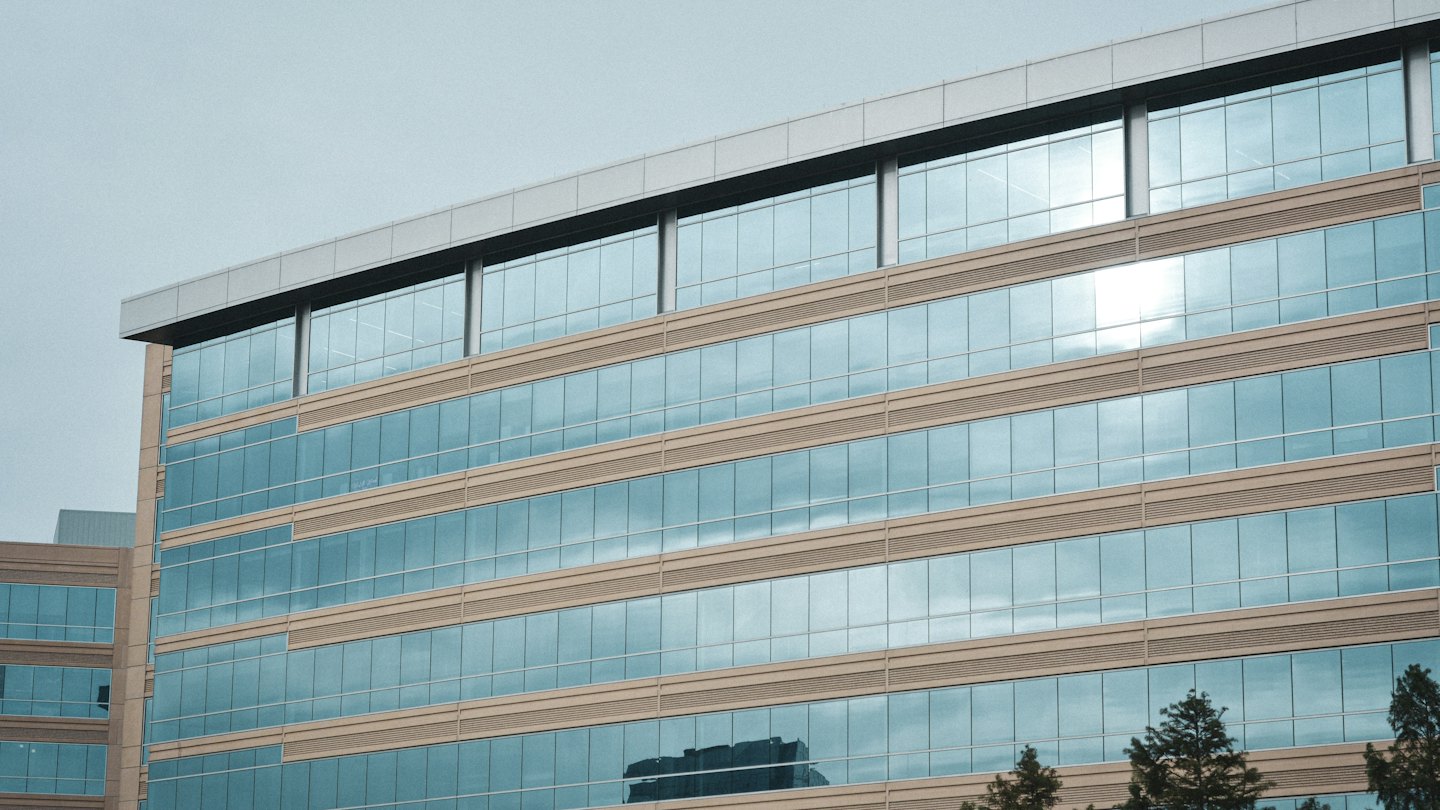 Modernes Bürogebäude mit blauen Glasfenstern und beigen Akzenten.
