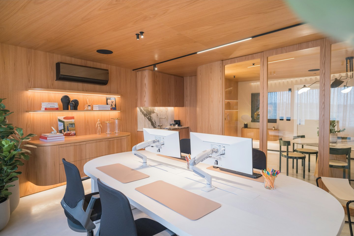 Modernes Büro mit weißem ovalem Schreibtisch und Computern.